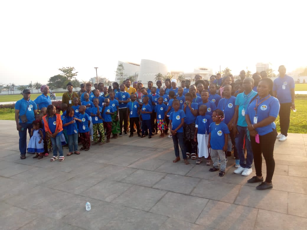 Groupe d’enfants et d’adultes en t-shirts bleus posant sur une esplanade au bord de l’eau en fin de journée