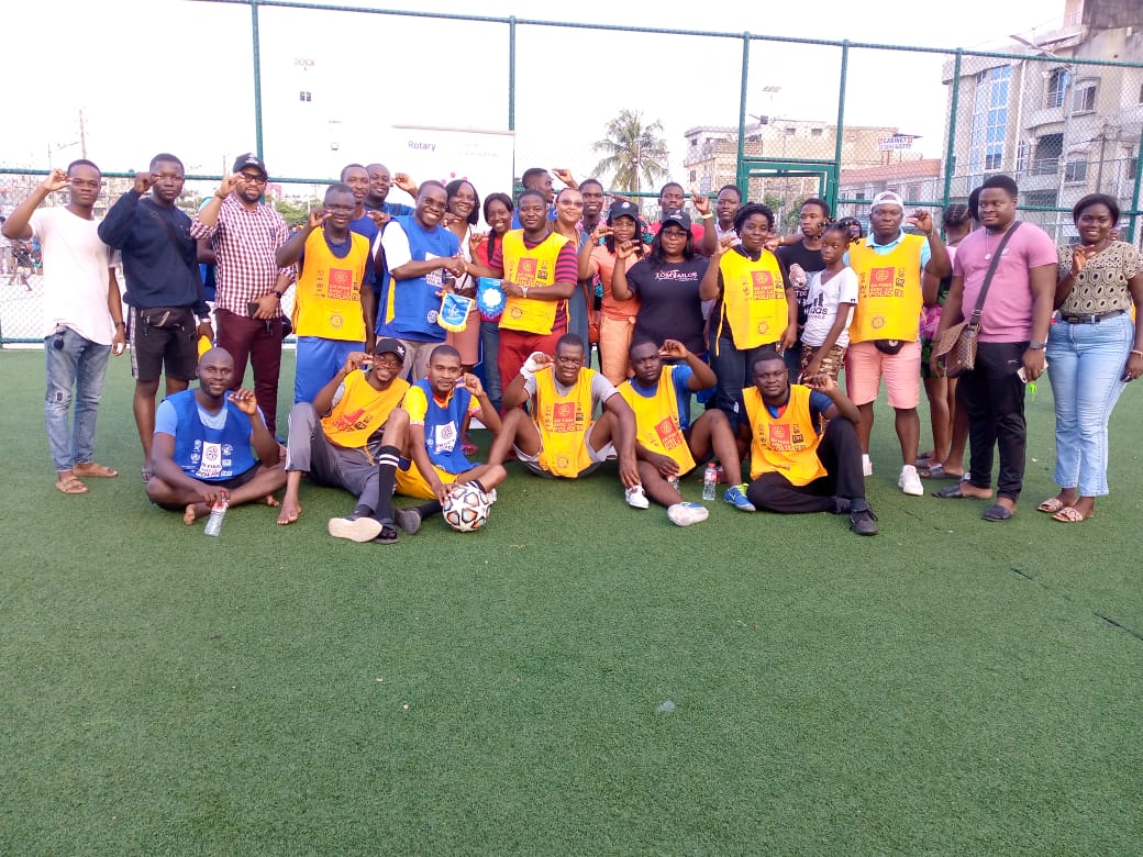 Groupe de jeunes posant sur un terrain de football en maillots jaunes et bleus avec un ballon au centre