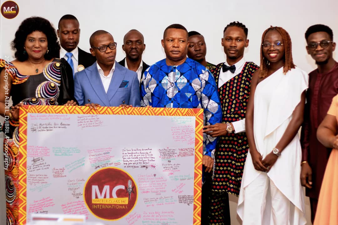 Un groupe de dix personnes posant autour d un grand panneau signé avec le logo MC International au centre