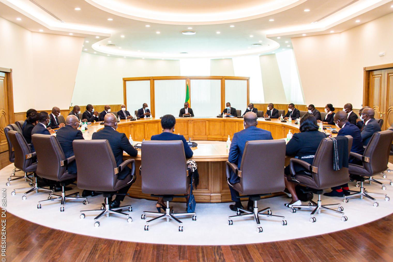 Personnes assises autour d’une grande table ovale lors d’une réunion dans une salle lumineuse et moderne