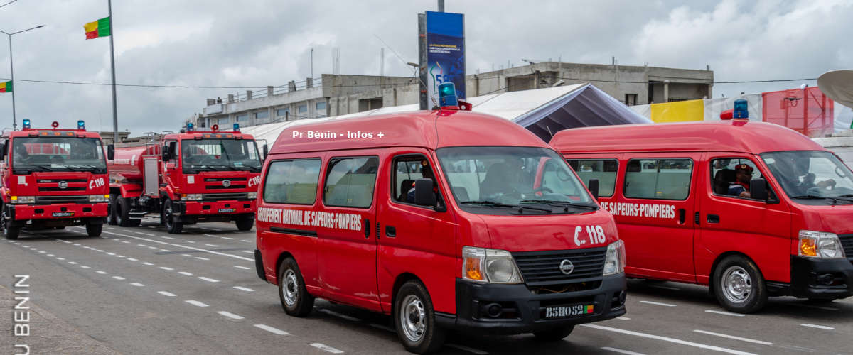 Plusieurs véhicules rouges de sapeurs-pompiers stationnés sur une large route sous un ciel nuageux