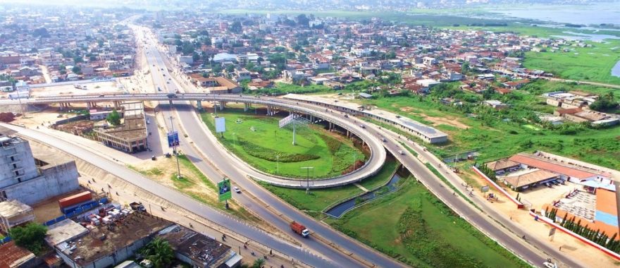 Vue aérienne d’un échangeur routier avec voies en boucle et route principale entourée de zones urbaines et d’espaces verts