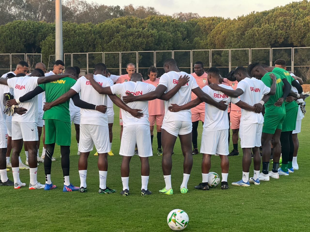 Joueurs en cercle bras dessus bras dessous sur un terrain de football pendant un entraînement