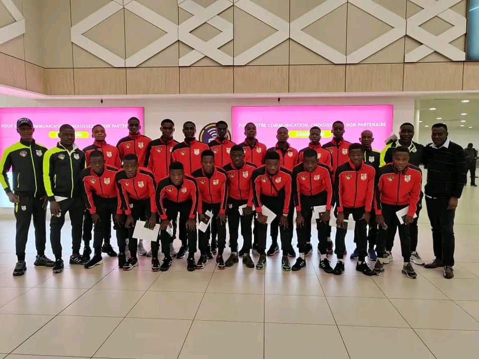 Un groupe de jeunes en tenue sportive rouge et noire posant dans un hall moderne avec des hommes en tenue noire sur les côtés