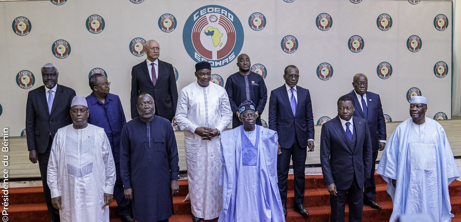 Onze hommes posant en groupe devant un mur orné de logos circulaires et un grand logo central avec une carte de l'Afrique