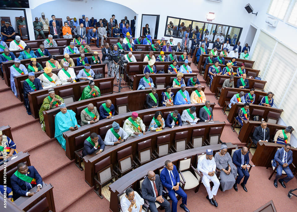Assemblée d’élus assis dans une salle en arc-de-cercle avec des femmes et des hommes portant des écharpes tricolores vert, jaune et rouge
