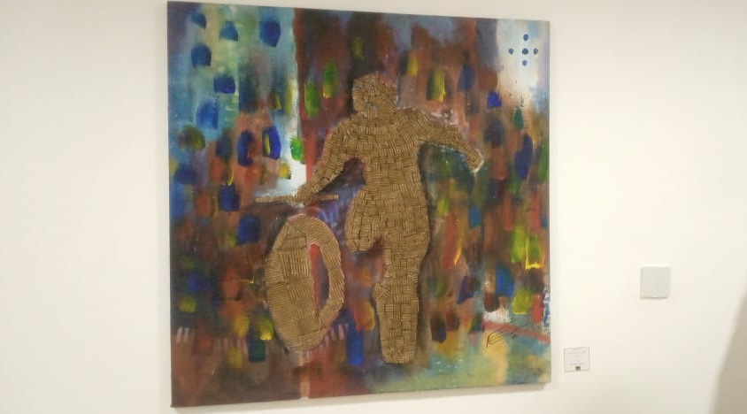 Peinture colorée avec silhouette en relief d'une personne courant derrière une roue sur un mur blanc d'exposition