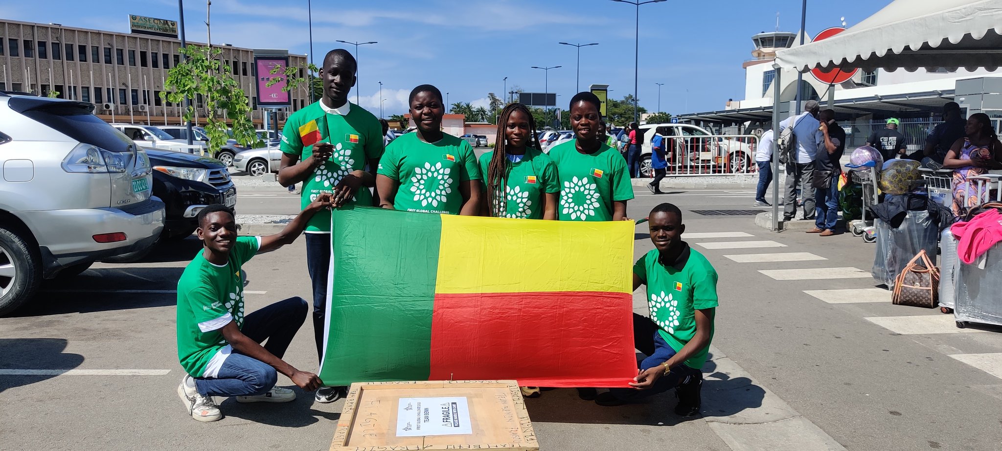 Groupe de six jeunes portant des tee-shirts verts posant dehors avec un drapeau tricolore vert jaune rouge posé devant eux