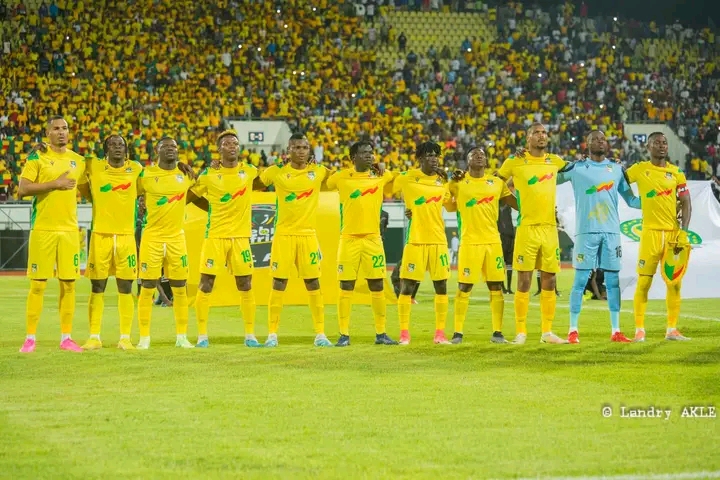 Onze joueurs de football en tenue jaune alignés bras dessus bras dessous sur le terrain avant le match