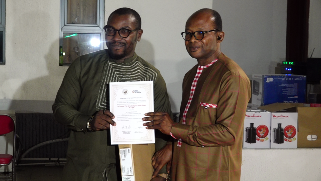 Deux hommes en lunettes tenant un certificat ensemble dans un intérieur avec des boîtes empilées en arrière-plan