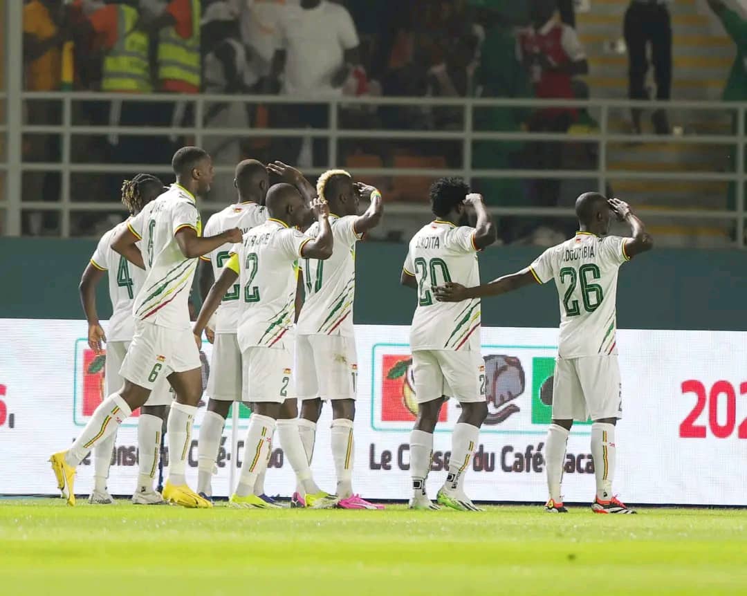 Joueurs vêtus de blanc célébrant ensemble en saluant les supporters dans un stade éclairé