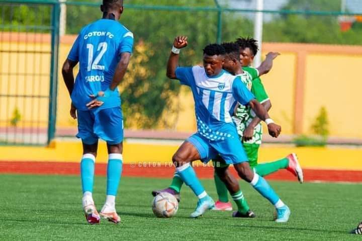 Deux joueurs en bleu et un joueur en vert au duel pour le ballon sur un terrain de football artificiel