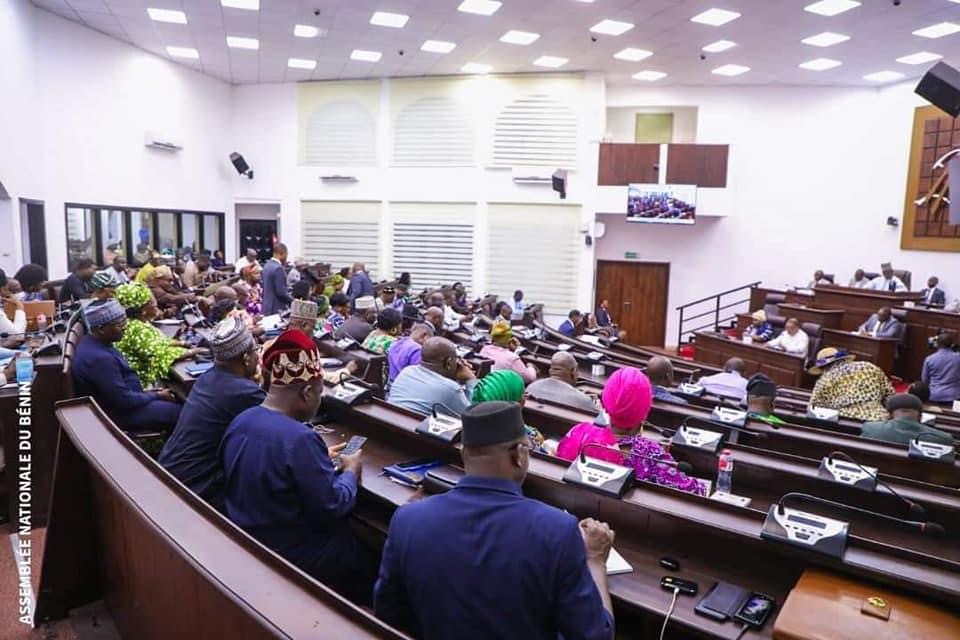Assemblée en session plénière avec des députés assis dans l’hémicycle et un orateur au pupitre face à eux