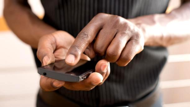 Mains d une personne utilisant un smartphone tactile noir avec un fond flou clair