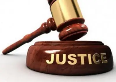 Un marteau de bois posé sur un socle avec l'inscription JUSTICE en lettres dorées