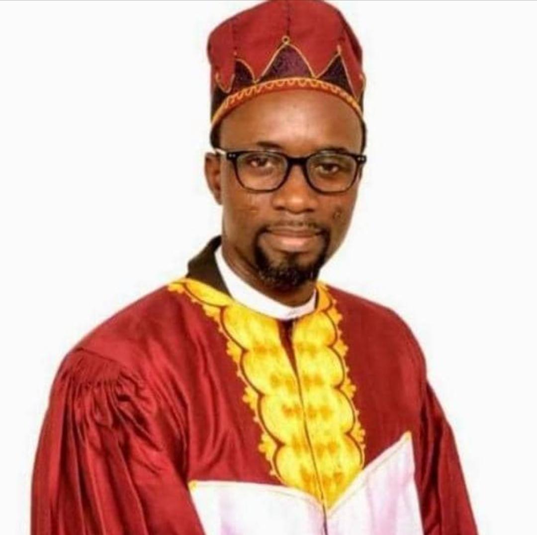 Homme portant des lunettes et un costume traditionnel rouge et jaune avec un chapeau assorti sur fond blanc