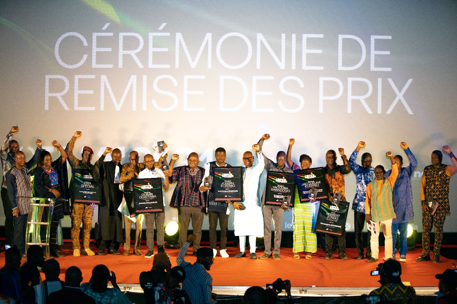 Plusieurs personnes debout sur scène brandissent des trophées lors d'une cérémonie de remise des prix