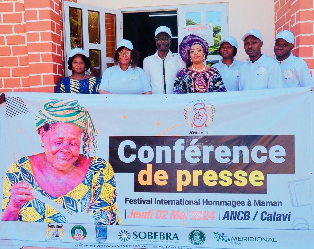 Sept personnes posent derrière une banderole annonçant une conférence de presse pour un festival international hommage à maman