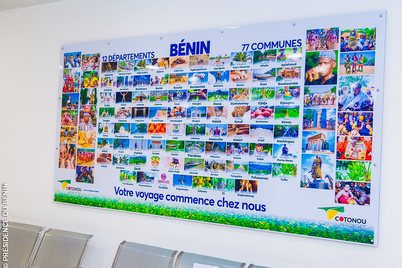 Carte colorée affichant 12 départements et 77 communes avec images touristiques et slogan promotionnel au mur d une salle d attente