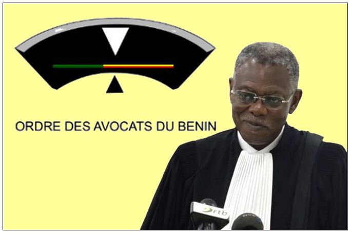 Un homme en robe d'avocat parle devant un micro avec un logo de l'ordre des avocats du Bénin en arrière-plan