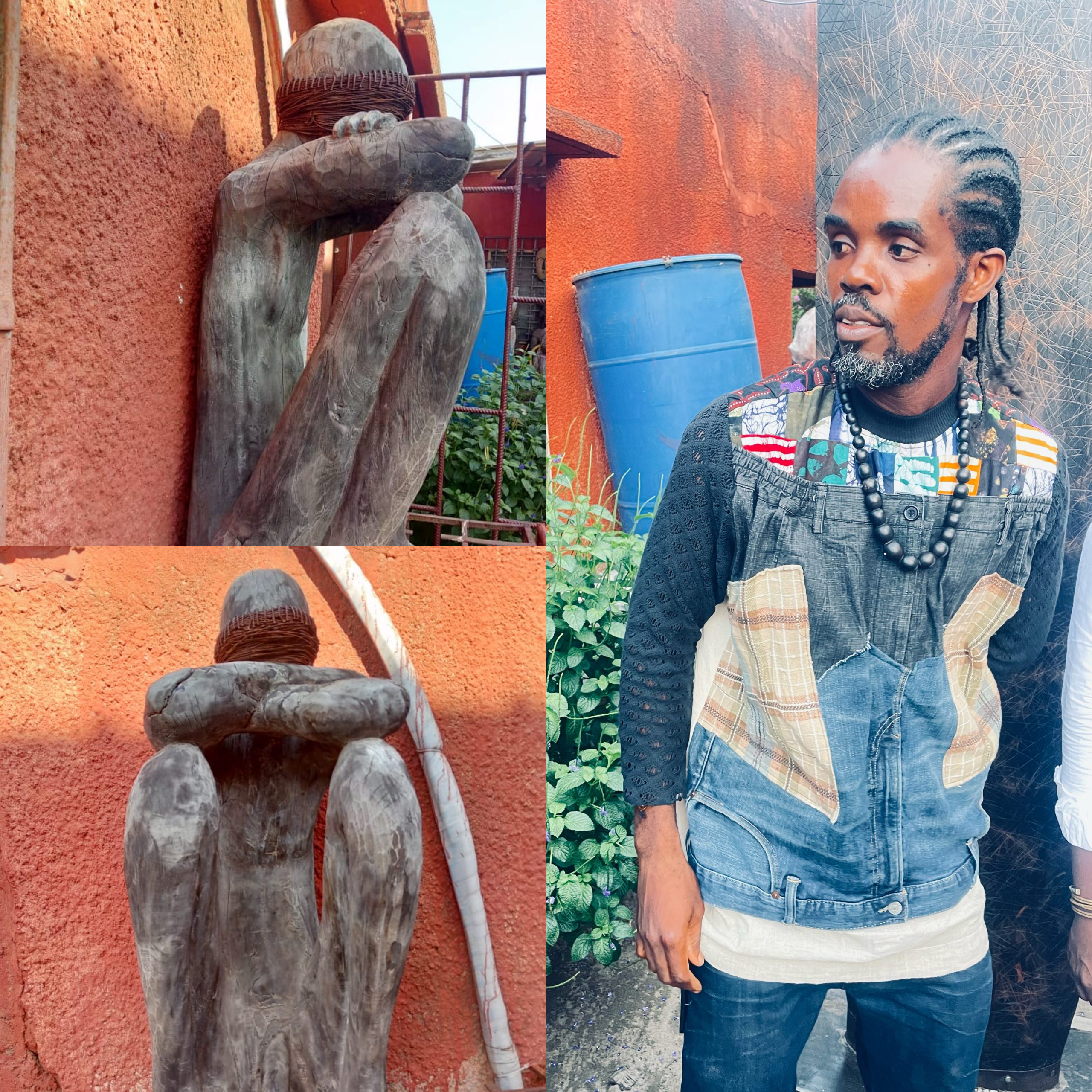 Sculpture en bois d’une figure assise et homme aux dreadlocks portant un vêtement patchwork et collier noir dans un jardin urbain