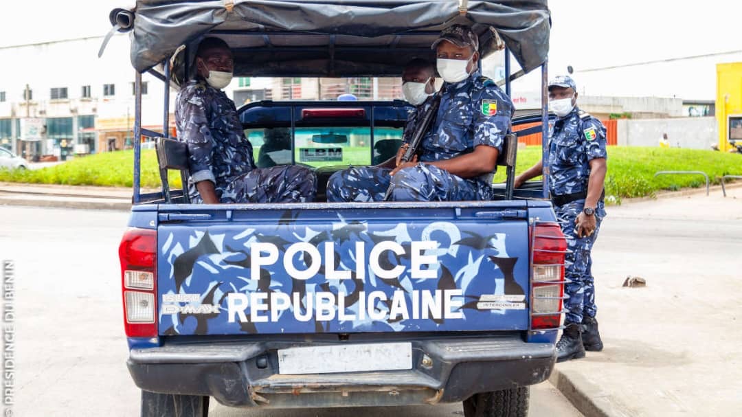 Quatre policiers en tenue bleue camouflée et masque sont dans et autour d’une camionnette de police républicaine bleue