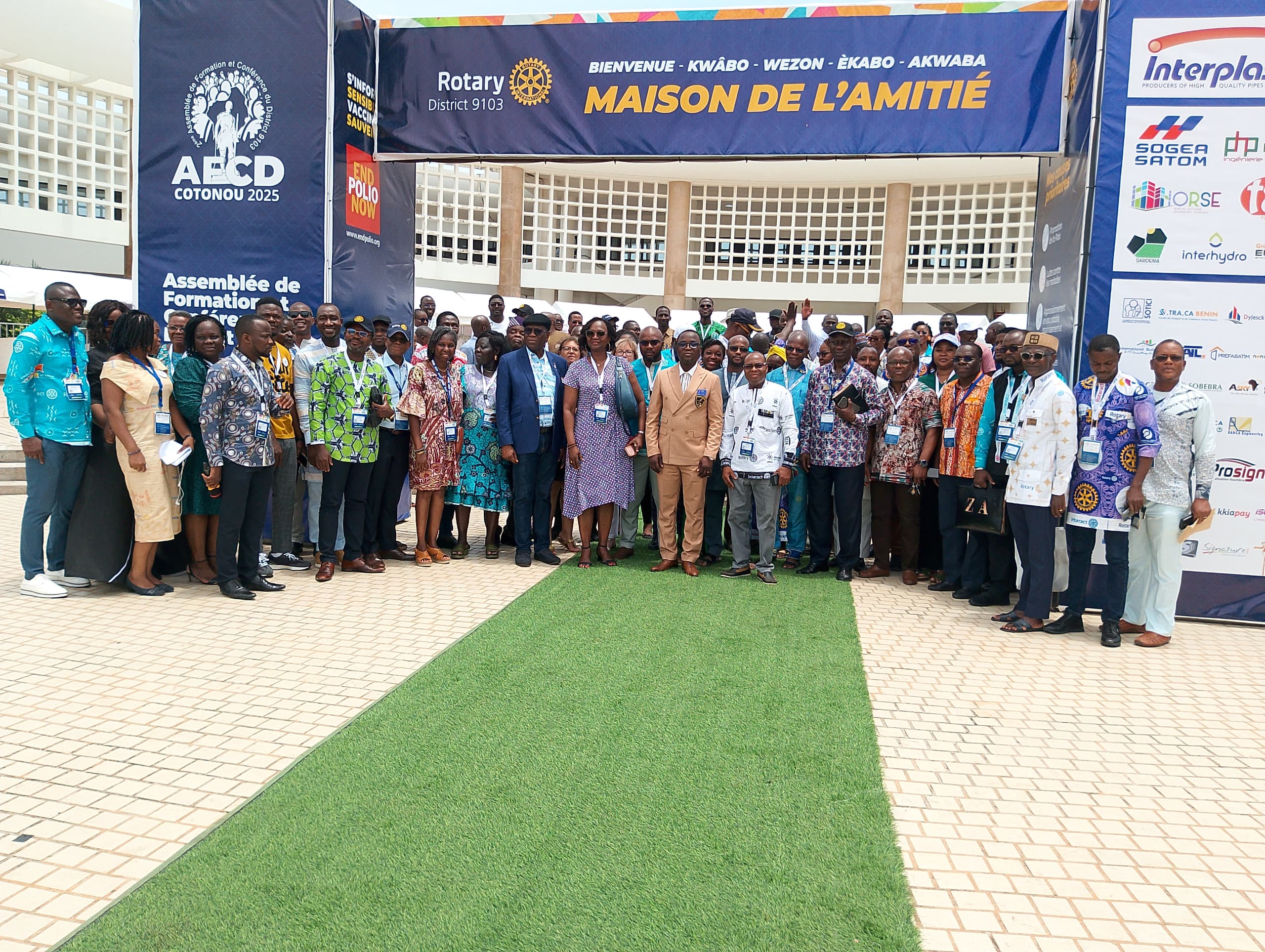 Groupe de personnes posant devant un stand avec une bannière "Maison de l'amitié" lors d'un événement professionnel