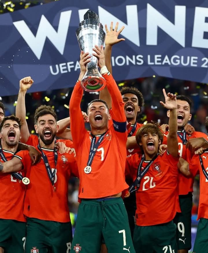 Joueurs en maillot orange brandissant un trophée et célébrant une victoire avec un panneau "WINNERS" en arrière-plan