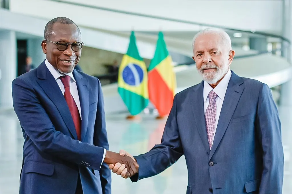 Deux hommes en costume se serrent la main devant les drapeaux du Brésil et d un pays africain