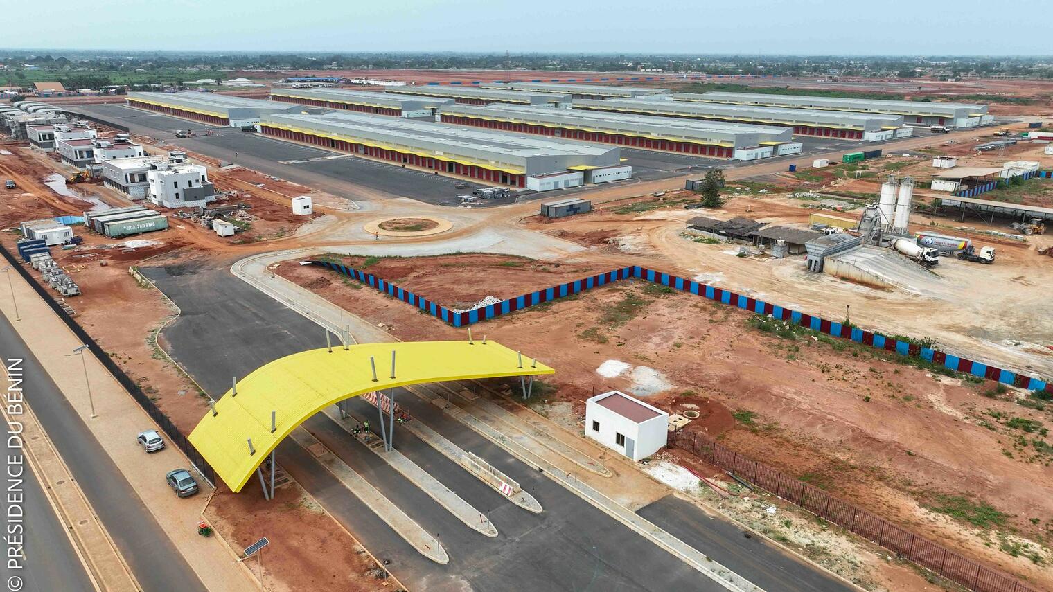 Vue aérienne d’un vaste marché de gros en construction avec des routes, des bâtiments et une grande entrée couverte jaune