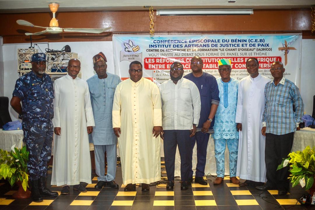 Un groupe d’hommes posant devant une bannière lors d’un événement sur les réformes constitutionnelles en Afrique