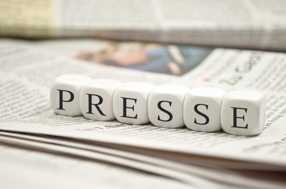 Dés cubes blancs alignés formant le mot PRESSE posés sur un journal ouvert