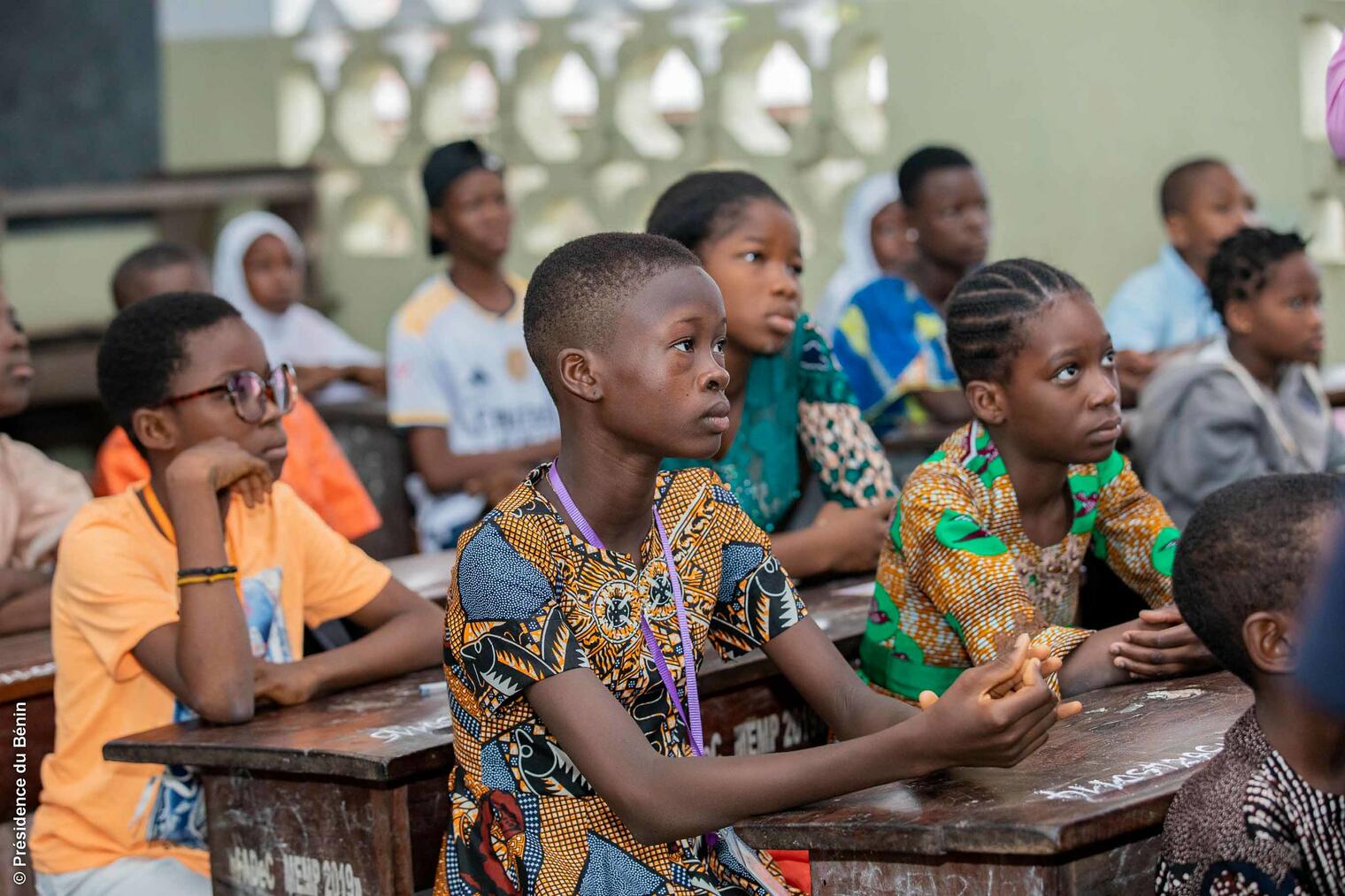 Des élèves assis aux bureaux d'une salle de classe attentifs et concentrés sur une activité