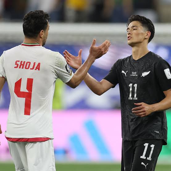 Deux joueurs de football de dos et de face se serrent la main sur le terrain après un match